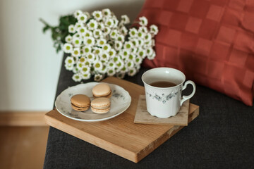 Morning coffee. Cozy composition in the interior. A cup of coffee on a wooden board and a bouquet of wild flowers. Still life concept. Copy space.