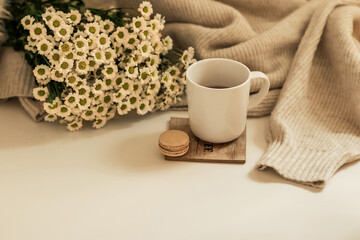 Morning coffee. A cup of coffee on a wooden table and an open book against a background of a bouquet of spring flowers. Still life concept. Cozy morning.