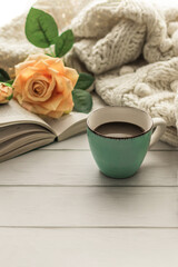 Morning coffee. A cup of coffee on a wooden table and an open book on the background of a bouquet of flowers. Still life concept. Cozy morning.