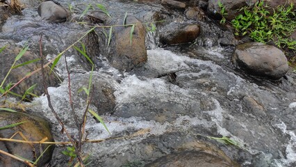 Abstract Defocused Blurred Background Photo of mossy rocks in a fast flowing river in the Cicalengka area - Indonesia. Out of Focus 