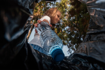 Environmental plastic pollution problem. Girl throws a plastic bottle into the trash