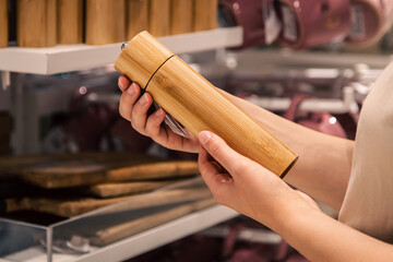 Wooden grinder for salt or pepper in female hands in a supermarket.