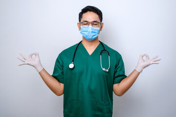 Calm and patient asian male doctor, nurse in scrubs staying relaxed, meditating with eyes closed...