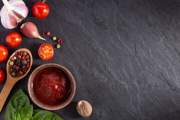 Tomato sauce and spice at black slate background table. Natural healthy homemade food concept