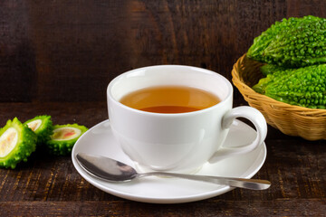 Bitter gourd or bitter melon tea in white cup on rustic wooden background. Scientific name is Momordica charantia. As a whole food and herbs for treating diseases.