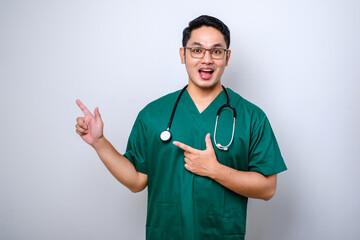 Smiling handsome asian doctor, nurse in scrubs and stethoscope, pointing fingers upper left corner, showing online clinic banner