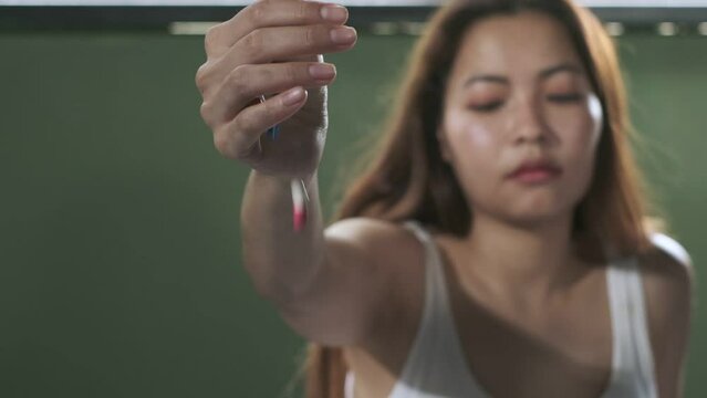 Hand of cute woman wearing white tank top overdosed sprinkle medicine pills to the floor,slow motion shot.