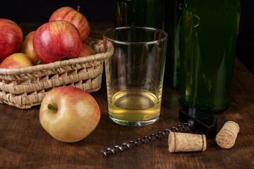 Close-up of a glass with a little cider, colloquially called culin, next to some apples, an opener and some bottles.