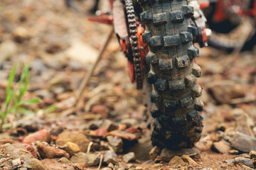 Part of a motocross wheel on a rocky road, with copy space for your individual text. A part of a dirt road dirt motorbike in the forest.