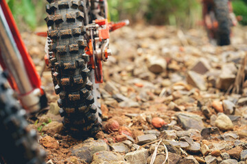 Part of a motocross wheel on a rocky road, with copy space for your individual text. A part of a dirt road dirt motorbike in the forest.