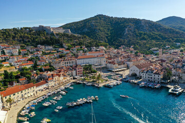 Fototapeta na wymiar Croatian Island Hvar Harbor in Summertime with multiple moored Yachts and boats. Hisanjola Fort overlooking the water.