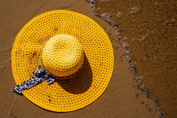 Żółty kapelusz na plaży, wakacje, piękny słoneczny dzień na plaży, morze, piasek. 