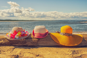 Trzy plażowe kolorowe kapelusze, słoneczny plażowy dzień, piasek.  - obrazy, fototapety, plakaty