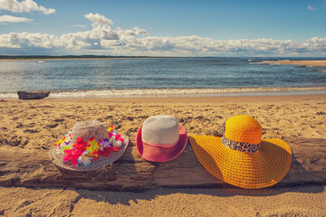 Fototapeta Trzy plażowe kolorowe kapelusze, słoneczny plażowy dzień, piasek.  obraz