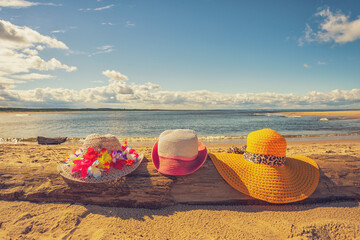 Trzy plażowe kolorowe kapelusze, słoneczny plażowy dzień, piasek.  - obrazy, fototapety, plakaty