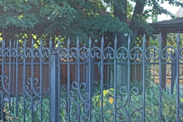 a fence made of black sharp iron forged pattern rods  on the wall in the street
