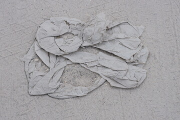 a piece of old dirty torn cellophane lies on gray sand in the street