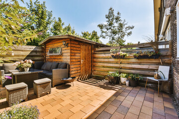 Neat paved patio with sitting area and small garden near wooden fence