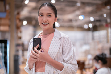 attractive adult asian female cashless online payment smartphone application progress purchase scanning qr code by touchless device new lifestyle shopping in cafe coffee shop store cashier counter
