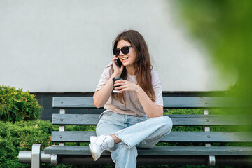 Business young woman sits on a bench and speaks on the phone.