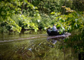 a motor boat floats on a calm river surrounded by greenery
