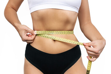 Cropped shot of a young slim woman measuring her waist with a centimeter isolated on a white...