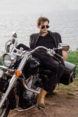 Fototapeta na wymiar Young handsome male is sitting on his motor bike outdoors