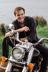 Fototapeta na wymiar Young handsome male is sitting on his motor bike outdoors