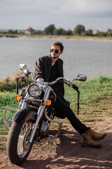 Fototapeta na wymiar Handsome man or young biker sitting and chilling on the bike chopper outdoors