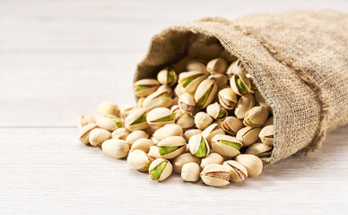 Pistachios in bag on white table with copy space.