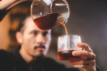 hipster barista making a drink coffee with drip or filter style by pouring hot water to brew a caffeine beverage from black bean in cafe restaurant business shop, using paper for aroma to a cup or mug