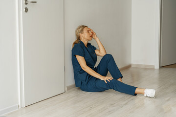 Tired nurse sits on floor in the lobby of medicine clinic after a hard dutty. High quality photo