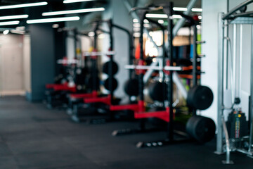 Fototapeta na wymiar Blurred Background Of Modern Sport Club Interior With Heavy Weight Lifting Equipment
