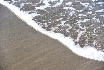 sea wave on the background of gray beach sand