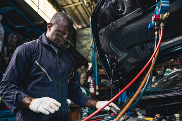 Fototapeta na wymiar Male mechanic wearing a uniform maintaining the car air conditioner.