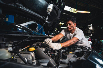 Fototapeta na wymiar Male mechanic wearing gloves checking the engine in the garage.