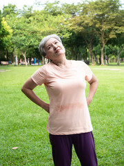 Portrait of mature asian woman 60s with low back pain at park outdoor.