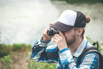 Obraz premium A man takes a photo on a vintage film camera in nature.