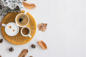 Autumn composition with cups of coffee and leaves on a white background.
