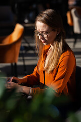 Young businesswoman in a cafe bar or restaurant. Freelancer girl working on laptop and having tea sitting at a window table.