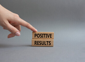 Positive results symbol. Concept words Positive results on wooden blocks. Beautiful grey background. Businessman hand. Business and Positive results concept. Copy space.