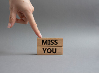 Miss you. Concept word Miss you on wooden cubes. Beautiful grey background. Businessman hand. Business and Miss you concept. Copy space.