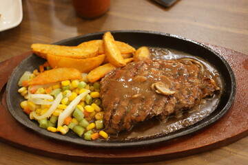Steak served on the hot plate with potatoes and vegetables