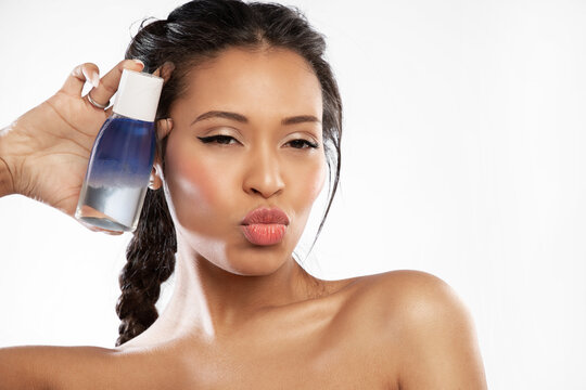 Playful young black woman hold jar with cleansing micellar water . Pretty happy girl showing bottle of lotion for removing makeup. Skincare cosmetics advertising.