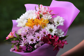 A bouquet of chrysanthemums (golden daisies) and  alstroemerias in violet wrapping