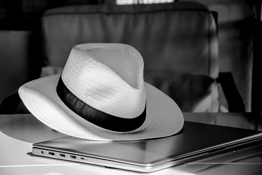 Straw hat on a switched off laptop in a dimly lit room