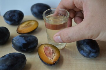 A glass of homemade plum brandy surrounded by ripe organic plums. Traditional Serbian national drink with a high alcohol content.