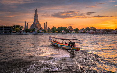 The passenger ship is turning around. In front of the Prang of Wat Arun the setting sun