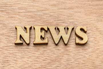 Wooden letter spelling the word NEWS on wooden background.