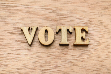 Wooden letter spelling the word VOTE on wooden background.
